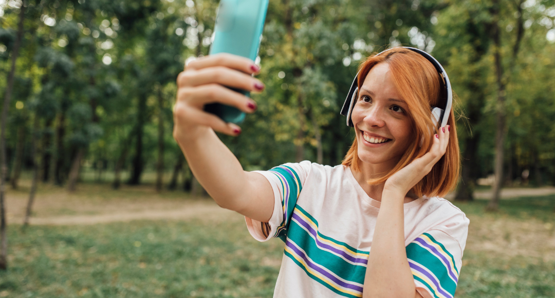 rødhåret pige i stribet t-shirt nyder godt af fri tale fra velkommen på sin mobil og snakker løs via en grøn telefon.png