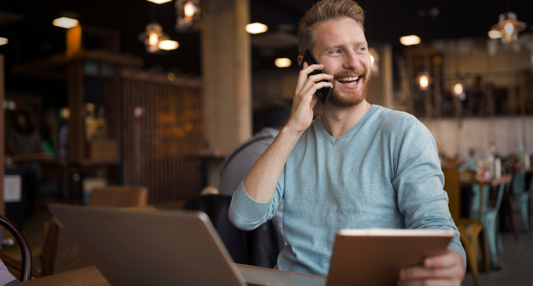 mand i lyseblå trøje snakker i telefon imens han tjekker gebyrer på sin elregning.png