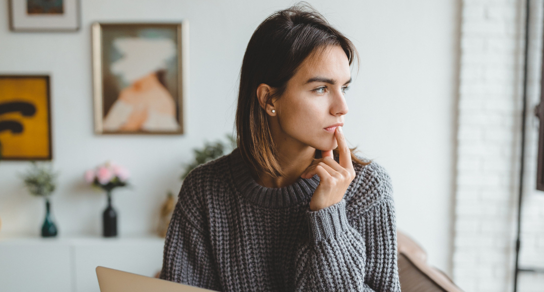 Mørkhået pige i grå sweater undrer sig over, hvorfor hendes gasregning svinger .png