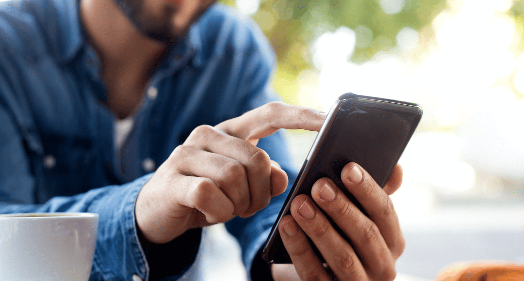 mand i blå denim skjorte, der sidder på sin mobil og skifter mobilabonnement til velkommen 