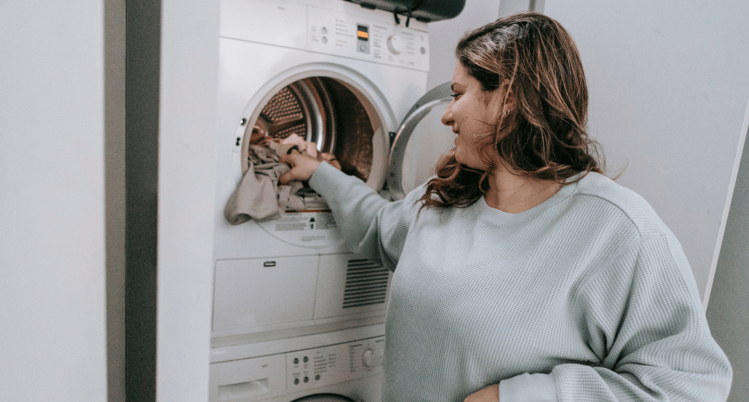 Mørkhåret kvinde vasker tøj og udnytter strømmen, når den er billigst, fordi hun har en variabel elpris hos Velkommen